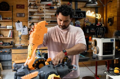 Mand samler et stort orange 3D-printet emne på en arbejdsbænk i et prototypeværksted