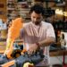 Mand samler et stort orange 3D-printet emne på en arbejdsbænk i et prototypeværksted